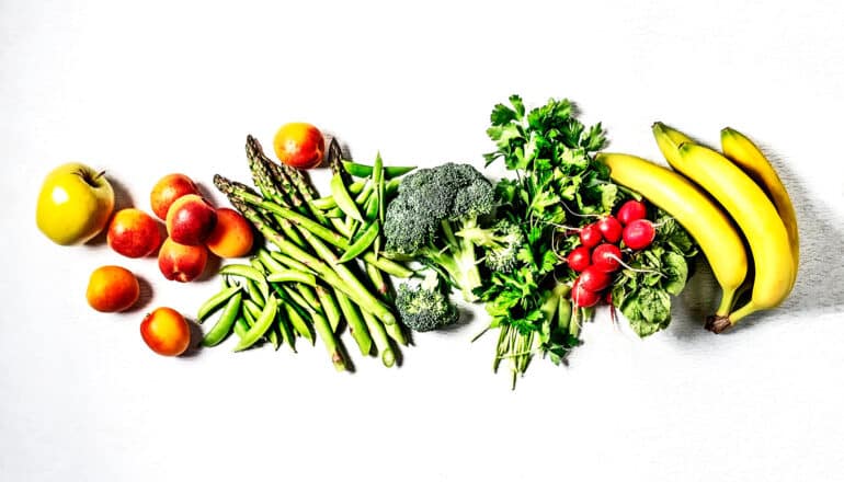 Various fruits and vegetables lined up on a white background.