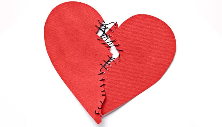 A heart shape cut from construction paper and then torn in half is sewn together with black thread.