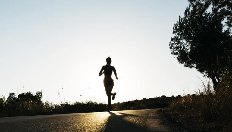 silhouette of person running on rural road