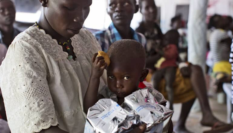 adult holds baby with food in hand