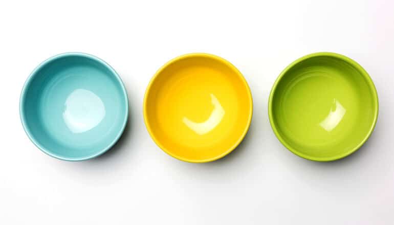 Three bowls on a white background, one blue, one yellow, and one green.