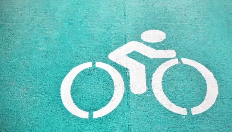 A green bike path has a white biking symbol showing a person on a bike.