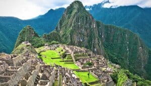 A shot of Machu Picchu from the air shows the ruins and the towering mountain behind them.