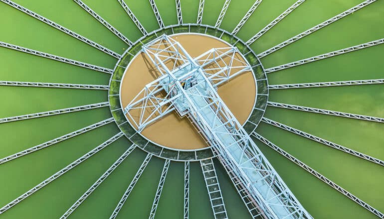 aerial view of wastewater treatment plant: blue metal arm over green water