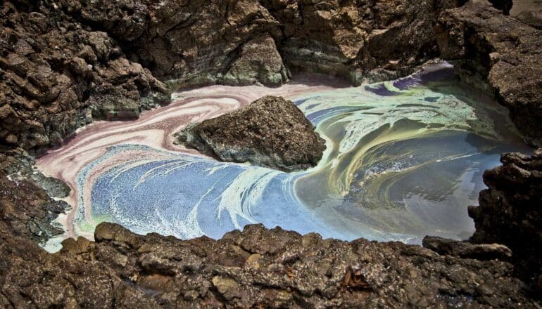 colorful patterns on surface of water in rock pool