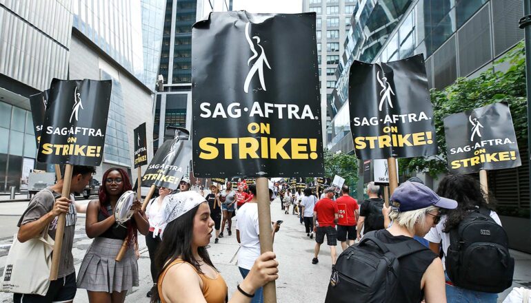 Actors hold picket signs that read "SAG-AFTRA on Strike!" as they march in New York.