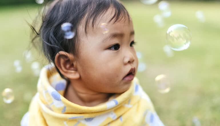 baby with bubbles looks to the side