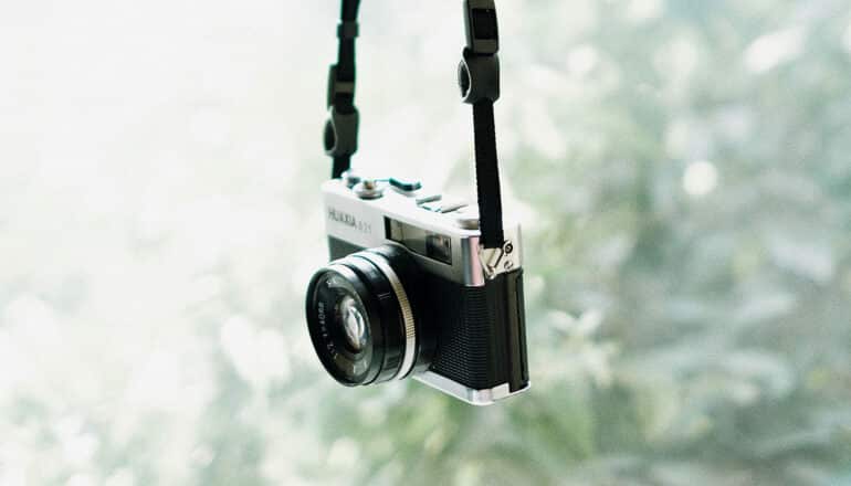 camera hands from strap in front of greenery