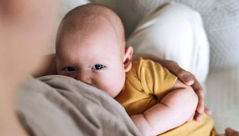 A baby looks up as a mother breast feeds.