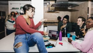 diverse group of young people in kitchen with laptops and water bottles