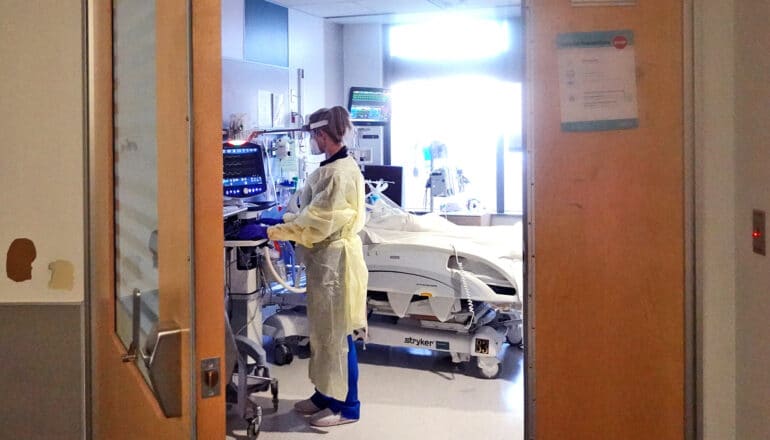 A doctor checks on a patient laying in a hospital bed.