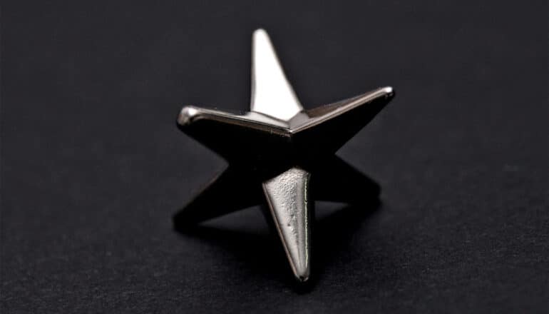 A silver star that looks black against a dark background.