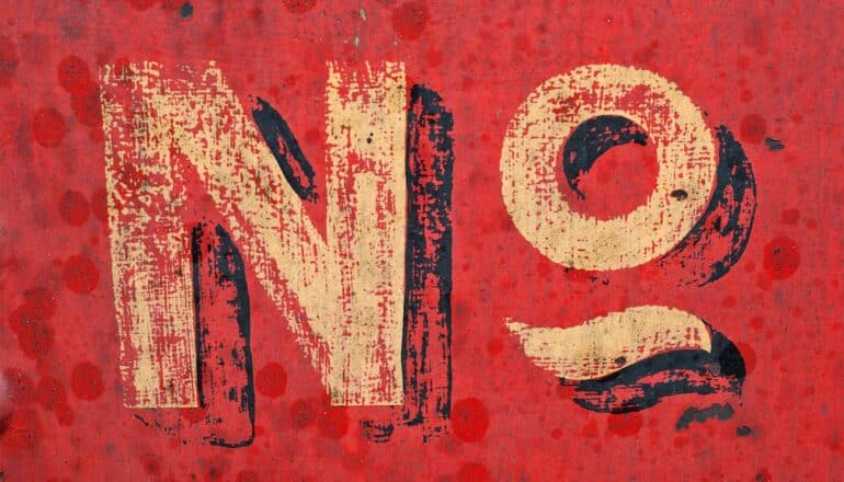 The word "No" painted on a red wall in shadowed text.