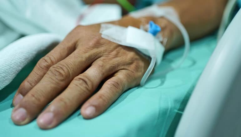 A hospital patient's hand with an IV running into it.