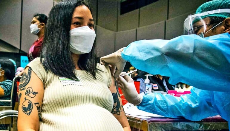 A pregnant woman gets a COVID vaccine dose from a health worker.