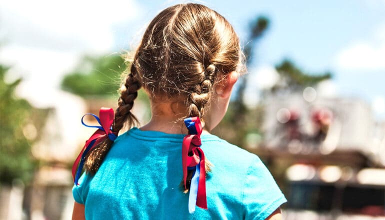 A young girl with two braids walks in a park.