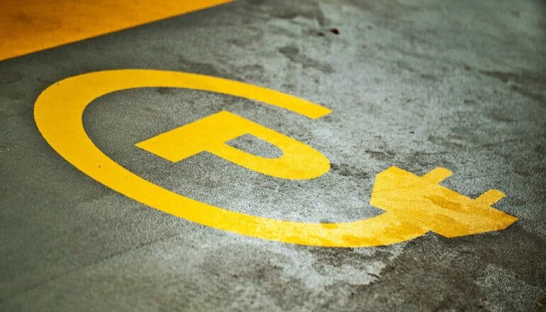 A parking spot has a symbol for electric car charging.