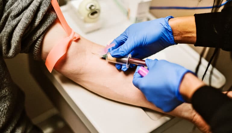 A health care worker draws blood from a patient's arm.