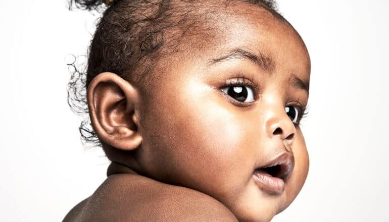 A baby's face looking right against a white background.