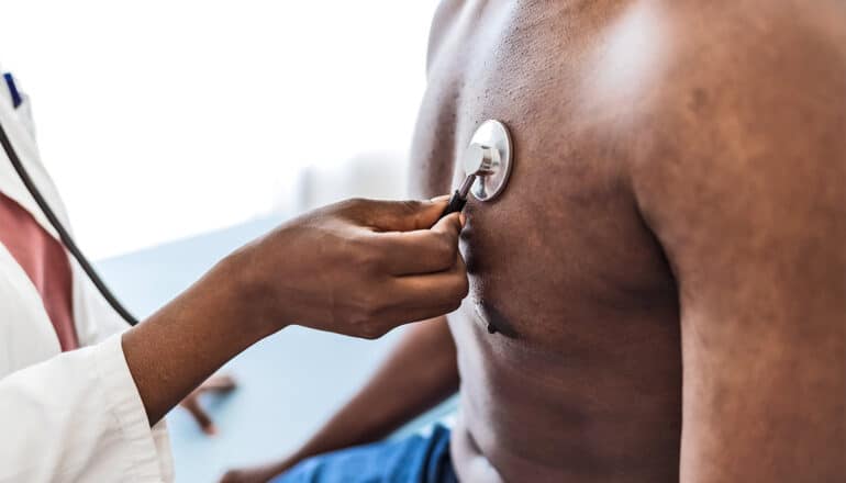 A doctor uses a stethoscope on a patient's chest.