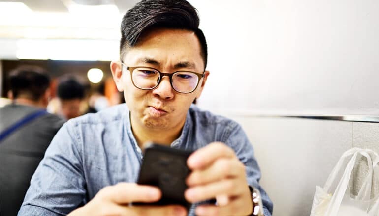 A man holding his phone looks annoyed.