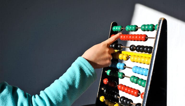 A child separates beads on an abacus.