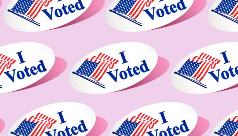 Several "I voted" stickers on a light pink background.