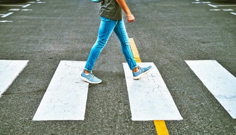 A person walks across a crosswalk on a street.