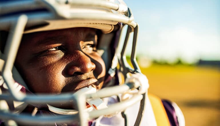 A young football player in a helmet and pads.