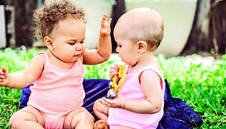 Two babies play outside at a park.