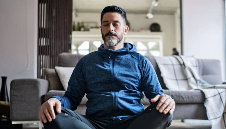 seated adult meditates in living room