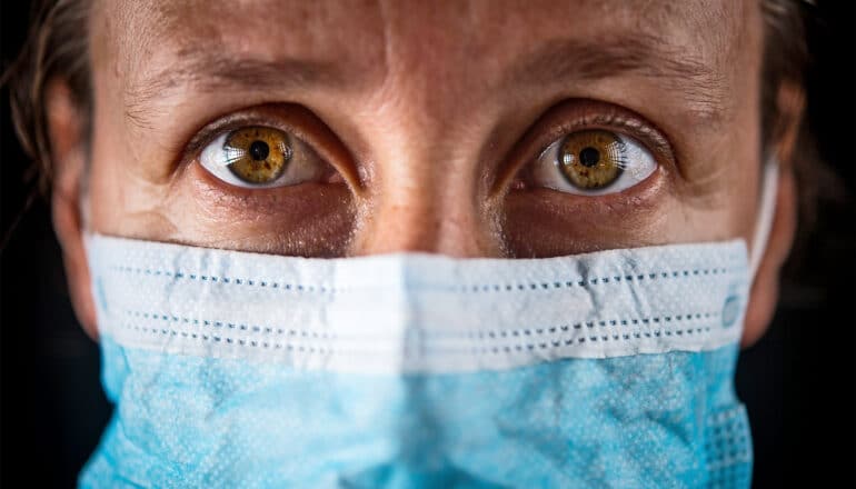 A woman looks worried while wearing a face mask.