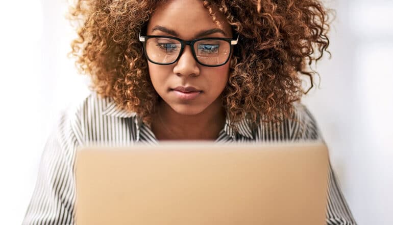 A young woman looks down at a laptop computer.