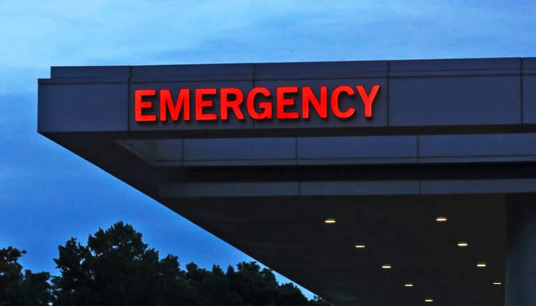 An emergency room sign over a hospital entrance is lighted red.