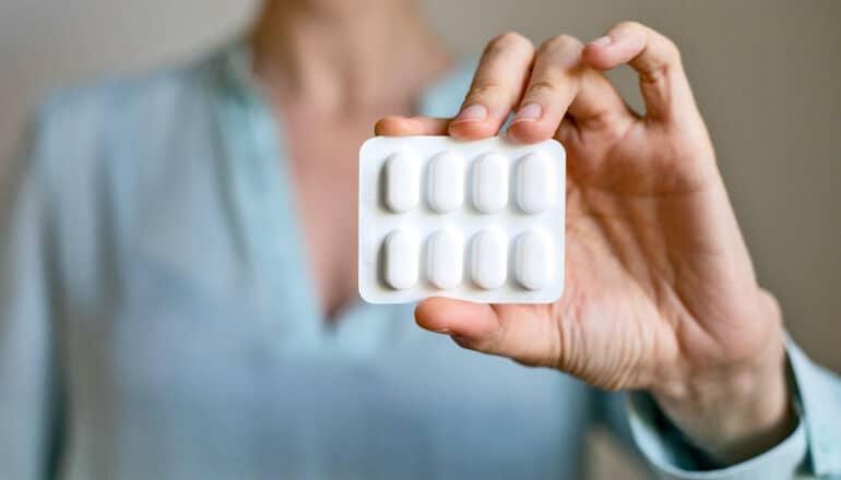 hand holds white blister pack of pills