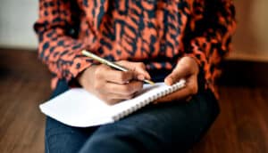 midsection of person holding pen and notepad