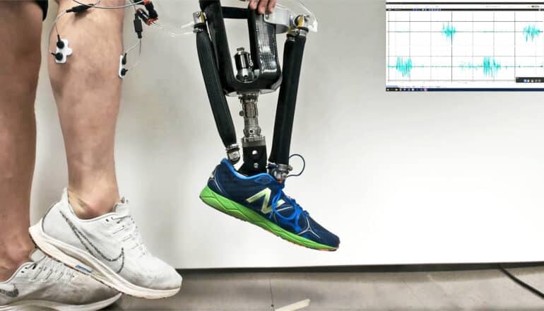 A person wears sensors on their leg and hold the robotic prosthetic ankle in front of themselves as it matches their movement.