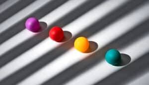 Four colorful balls sit in diagonal shafts of light and shadow.