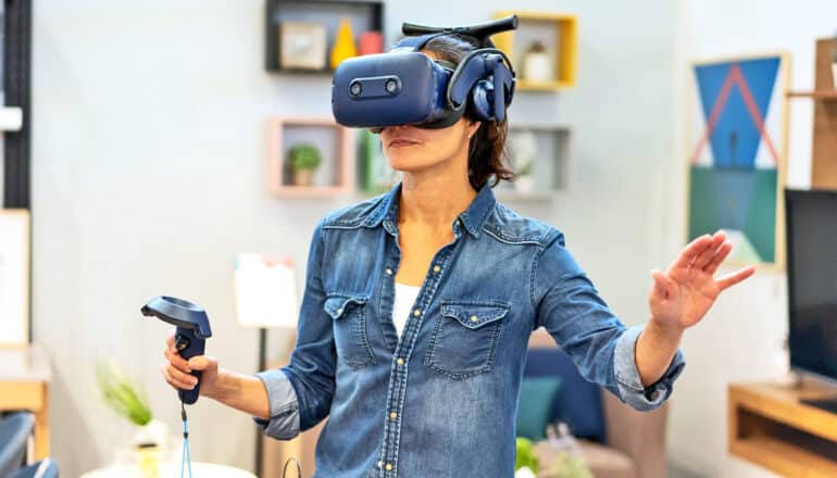 A woman using a virtual reality headset in a living room.