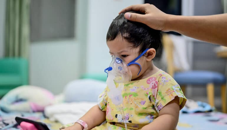 A young child has a respirator mask on at the hospital.