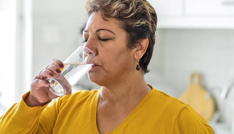 A woman drinks a glass of water.