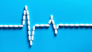 White pills arranged in a spiking line to look like a heart monitor readout.