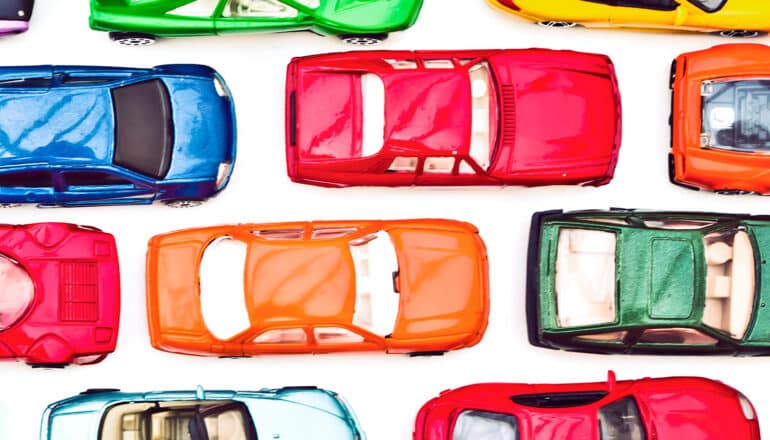 Toy cars sit in rows on a white surface as if in a traffic jam.