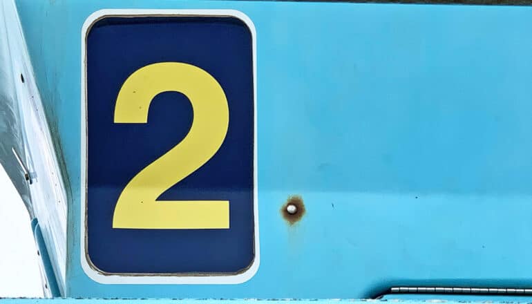 A number two on a sign on a blue wall.