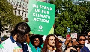 Protesters urging climate action, with one holding a sign that reads "We stand up for climate action."