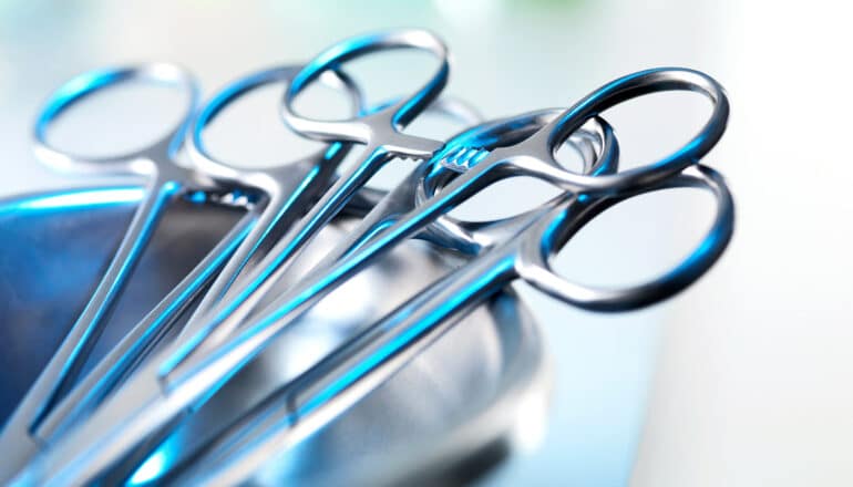 Surgical tools sit in a metal tray.