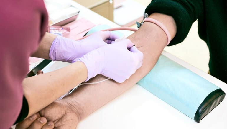 A health care worker takes blood from a patient.