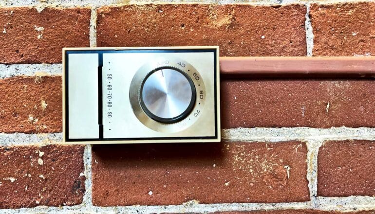 A thermostat on a brick wall.