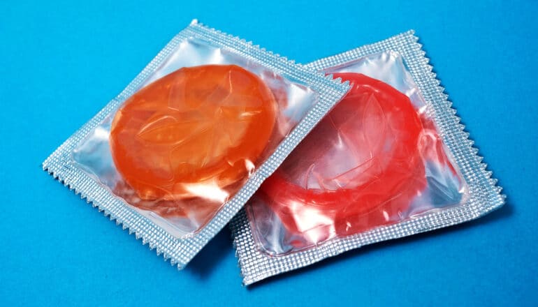 Two colorful condoms in packets on a blue background.