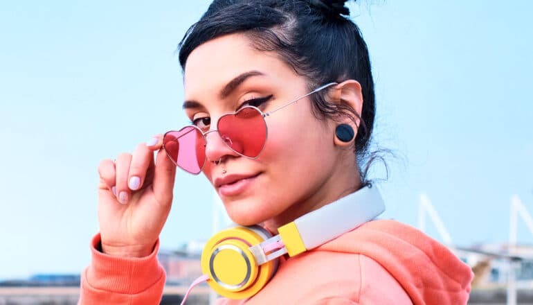 A woman wearing heart shaped glasses looks at the camera.